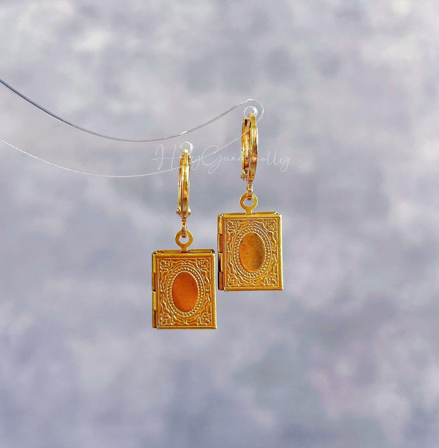 a pair of gold colored book earrings the book can be open
