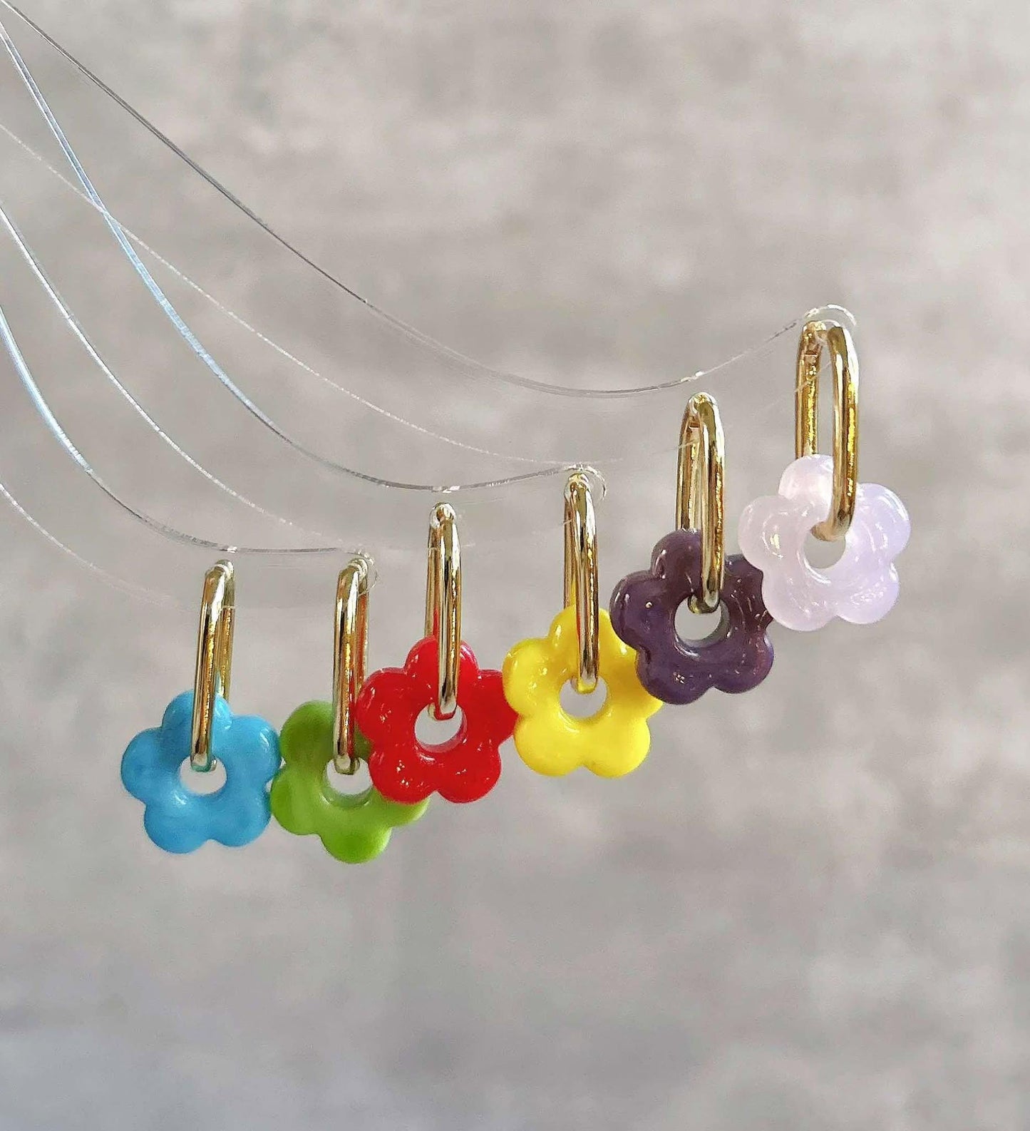 The Dainty 14K Gold Plated Flower Hoop Earrings are available in six vibrant colors—pink, purple, yellow, red, green, and blue. These playful yet elegant earrings add a colorful touch to any outfit, perfect for both casual and special occasions.